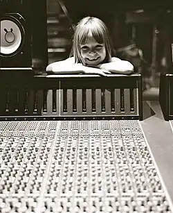 A monochromatic picture of Connie Talbot putting her arms and head on audio equipment