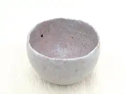 Handmade ceramic tea bowl with rough texture and asymmetry