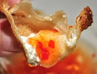 Inside, showing the crisp shell, white filling, and golden dipping sauce.
