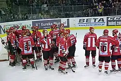 Post-game celebration by hockey players surrounding their netminder