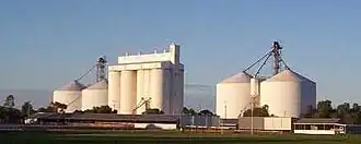 The rising sun catching the Crystal Brook grain silos on a clear winter's morning; the town sports oval in the foreground