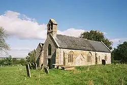 Stone building with arched windows. In the foreground are gravestones.