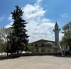 A building in Cumhuriyet next to a pine tree and a brick plaza.