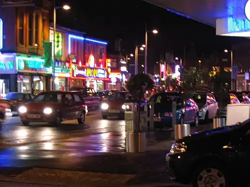 Night-time view of the Curry Mile on Wilmslow Road, Rusholme, Manchester, a major South Asian restaurant corridor.