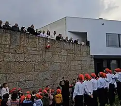 A basket being lowered from a wall to waiting students