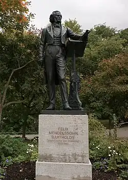 Bronze statue of a formally dressed man standing near a lectern