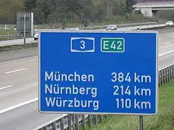 A road sign with three city names containing ü, Raststätte "Weiskirchen" on the A3 autobahn, south-east of Frankfurt-am-Main, Germany