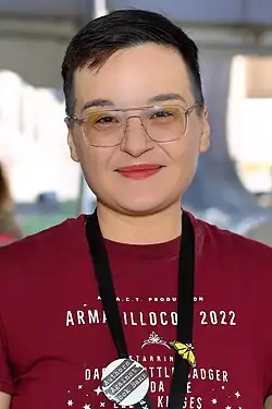 Portrait of Darcie Little Badger, a young Apache woman with short black hair wearing a maroon T-shirt.