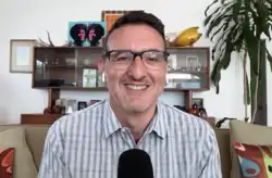 David Dayen, a man with brown hair, light skin, and glasses sits in front of a microphone smiling