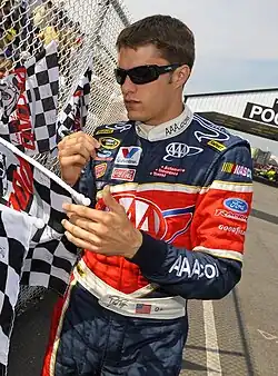 Picture of man signing his autograph on a chequered flag.