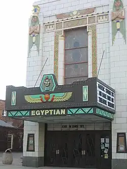 Entrance of an Egyptian theater decorated with pharaoh figures, winged sun motifs, and colorful Egyptian Revival designs above the marquee