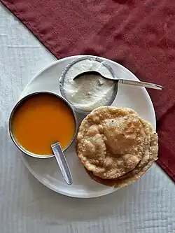 A puri on a plate with two bowls of puddings
