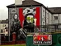 Gable-end mural, vandalised with green paint,[note 21] showing Raymond McCartney and a female hunger striker from 1980
