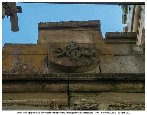 Detail looking up towards carved shield relief bearing a monogram datestone reading ‘1890’ - Birkwood Castle - 05 April 2025