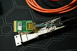 Disassembled QSFP transciever showing the optical fibre connection and electronics