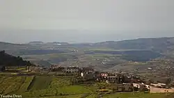 Pale skies with a village and mountains.