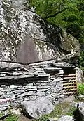 Adding a dry stone wall to convert the space under a large rock into a functional building near Bignasco, Switzerland