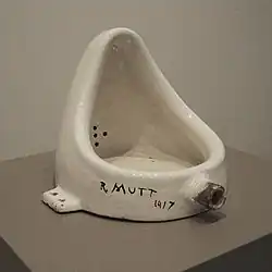A white porcelain urinal with "R. Mutt" in messy writing