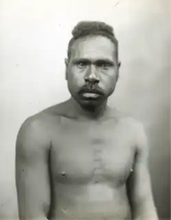 Portrait photograph of a shirtless Aboriginal man