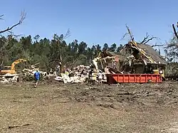 A significantly damaged home, with nearly half the structure missing.