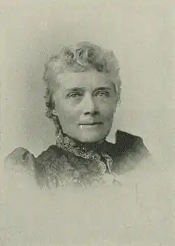 B&W portrait photo of an elderly woman wearing a dark, high-collared blouse with her hair in an up-do.