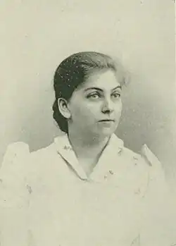 19th-century B&W portrait photo of a woman with her hair in an up-do, wearing a dark, fitted blouse.
