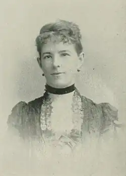 19th-century B&W portrait photo of a woman with her hair in an up-do, wearing a dark, fitted blouse.