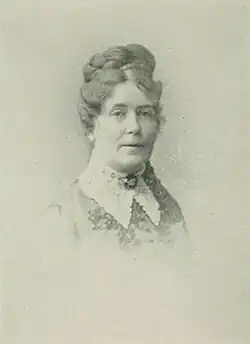 B&W portrait photo of a middle-aged woman wearing a pale, high-collared blouse with her hair in an up-do.