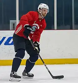 Ice hockey player in a Seattle Kraken practice jersey with his stick on the ice