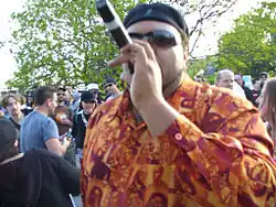 Egyptian Lover performing outdoors wearing an orange patterned shirt and sunglasses, holding a microphone