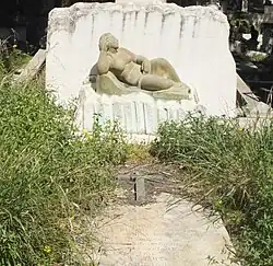 A marble tombstone sculpture of a nude figure.