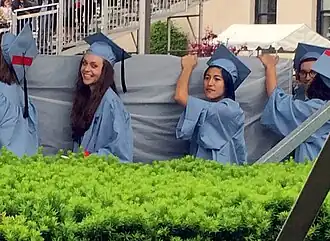 Companions of Emma Sulkowicz and the artist herself carrying the mattress to the graduation as a complaint
