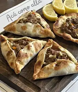 Empanadas àrabes, open-faced like sfiha and served with lemons