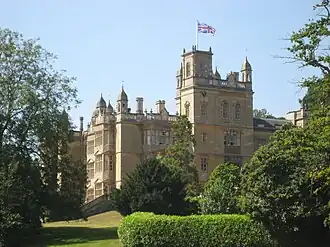 A mansion surrounded by trees and hedges.