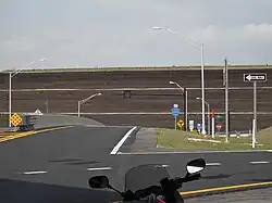 A "T" intersection between SR 414 and CR 437A. A sign points drivers heading to SR 429 southbound to the left. A large brick wall is behind the intersection.