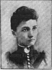 19th-century B&W portrait photo of a woman with her hair in an up-do, wearing a dark, fitted blouse.