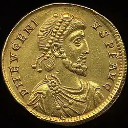 A color photograph of a gold coin with a king's engraving and Greek lettering