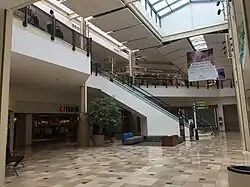 Section of the mall that expanded in 1997–1999 from one to two levels. The old layout only had a lower level with the escalators going up to a higher one-level section. After 1999, the section in front of the escalators expanded to two floors.