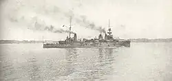 A large light gray ship passes slowly through calm waters.
