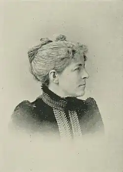 19th-century B&W portrait photo of a woman with her hair in an up-do, wearing a dark, fitted blouse.