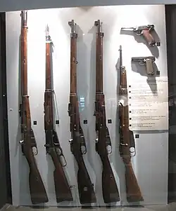 Display of military firearms; second rifle from the left is a Winchester Model 1895 manufactured under contract for the Russian Empire army.