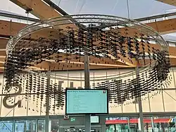 A ring of many small metal fish dangling around a departure board.