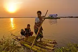 A woman using a raft to transport her daughter and goats
