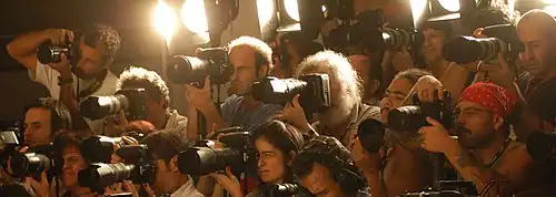 Photographers at a Brazilian fashion show lean forward with the cameras