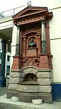 elaborate drinking fountain on the side of a large urban building