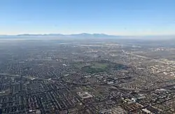 An aerial view of Fountain Valley on a fairly hazy afternoon in August 2011, looking NNW toward the San Gabriel Mountains. The green patch in the middle is Mile Square Regional Park.