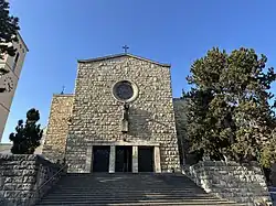 Stone church with a cross under a blue sky.