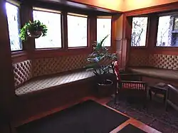 Seats in the living room. The seats themselves are upholstered, and there are polygonal glass windows behind them, which protrude outward.