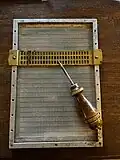 metal washboard slate with a removable two line slate. A stylus rests on the slate which is about half the length of the full page slate.
