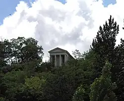 View of a temple in the center of a wood, at the top of a hillside.